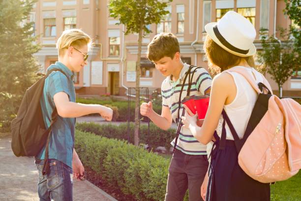 group of happy teenagers 13, 14 years walking along the city street, friends greet each other at a meeting. - friendship early teens 13 14 years city street imagens e fotografias de stock