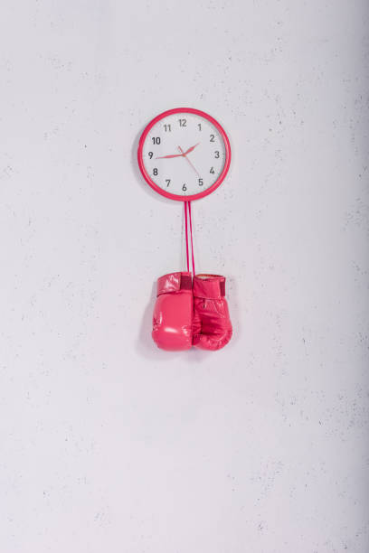 istock pink boxing gloves hanging at pink wall clock on white 972506944