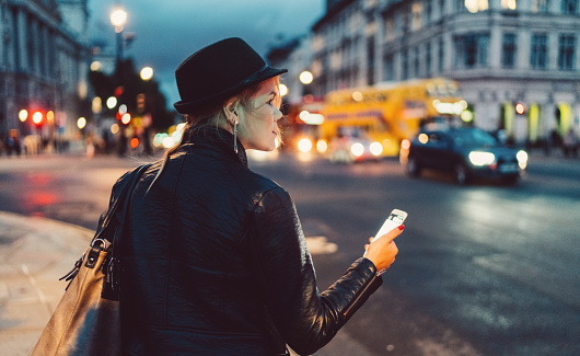 Girl in the city of London using mobile app for taxi calling