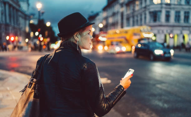 kobieta w londynie w nocy czeka na taksówkę - london england england street light telephone zdjęcia i obrazy z banku zdjęć