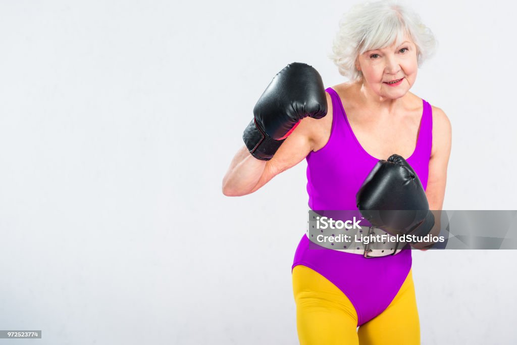 sportive senior lady boxing and smiling at camera isolated on grey 1980-1989 Stock Photo