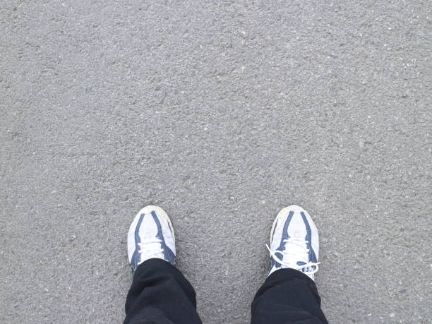 istock Black trousers and sneakers on the asphalt 972526406