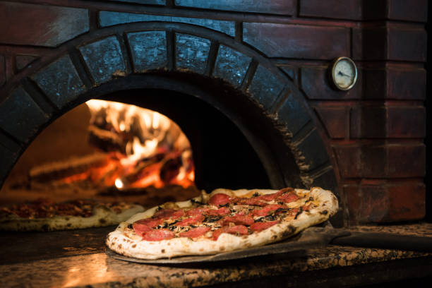 nahaufnahme der garprozess rohe pizza im holzofen im steinofen - brick oven stock-fotos und bilder