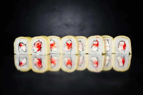 Sushi roll on dark background made of Nori, Marinated rice, Philadelphia, Cheese, Massa Caviar, Shrimp Tiger is boiled, Cheese Tenero, Walnut Sauce. Sushi menu. Japanese food. Close-up. Copy space