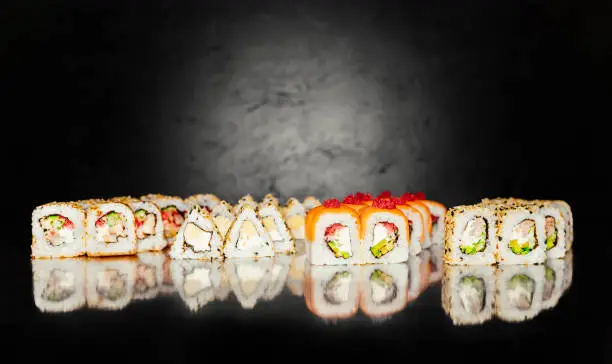 Top view of Japanese Sushi. Sushi rolls set on black dark background. Space for text. Sushi menu. Japanese food. Free-space. Close-up.