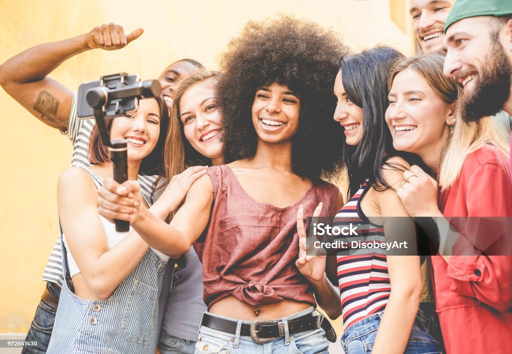 Happy millennials friends making video feed with smartphone outdoor - Young people having fun with new technology trends - Youth lifestyle and social media concept - Focus on black african girl face Teenager Stock Photo