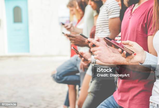 Group Of Friends Watching Smart Mobile Phones Teenagers Addiction To New Technology Trends Concept Of Youth Tech Social And Friendship Focus On Closeup Phone Stock Photo - Download Image Now