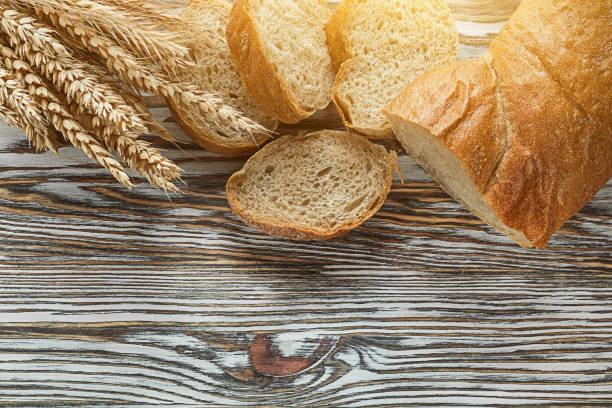 istock Crusty sliced bread rye ears on wooden surface 972542118