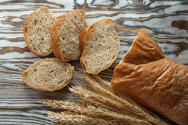 istock Crusty sliced bread wheat ears on wooden surface 972542142