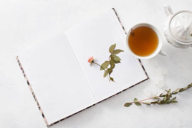 istock A Cup of tea and an open Notepad with dried flowers on a white table 972544632