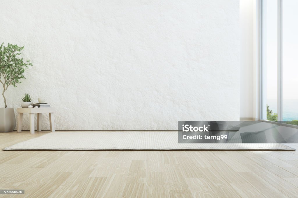 Sea view living room of luxury summer beach house with glass window and wooden floor. Empty rough white concrete wall background in vacation home or holiday villa. 3d rendering of hotel interior. Living Room Stock Photo