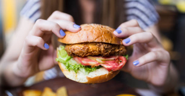 istock woman holding a big hamburger 972553188