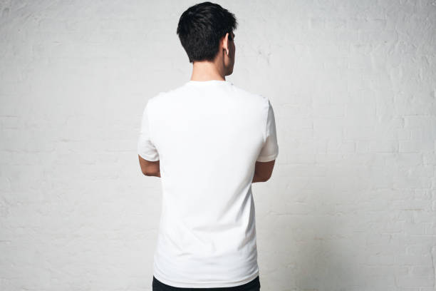 istock Young guy in blank white t-shirt, back side, horizontal studio portrait, empty wall 972560244