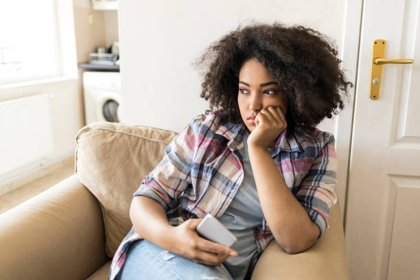istock Pensive young woman using smart phone at home 972565870