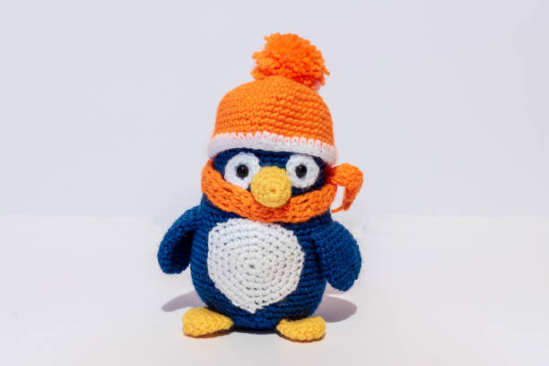 Handmade stuffed toy penguin, in orange hat.