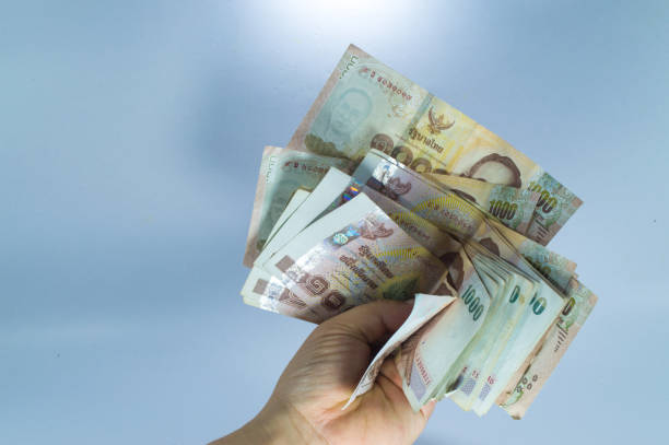 istock Thai baht banknotes in hand isolated on blue background 972576006