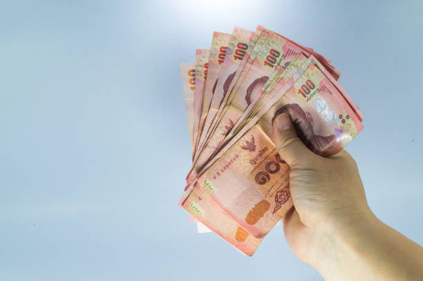 istock Thai baht banknotes in hand isolated on blue background 972576234