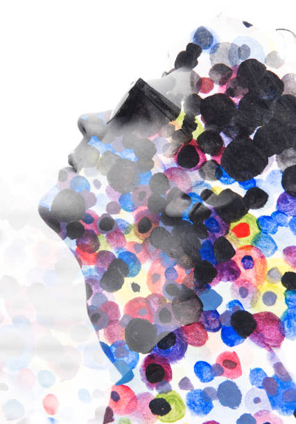 istock Paintography. Double exposure. Close up of man with glasses and a sad expression dissolving behind hand painted colorful watercolor dots 972581848