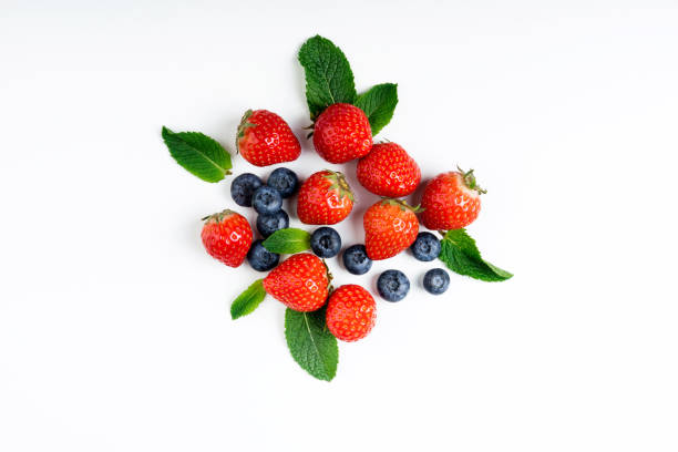 Fresh berries on white background, top view. Strawberry, blueberry and mint leaf,