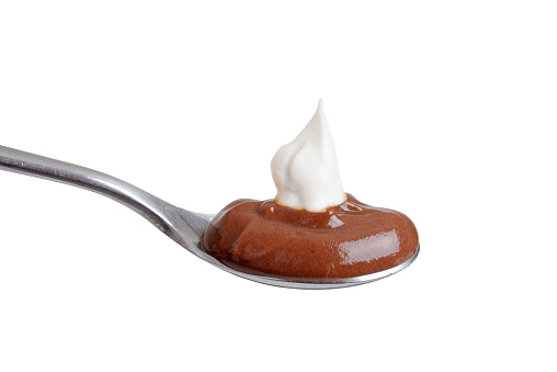 isolated spoon of chocolate pudding with whipped cream