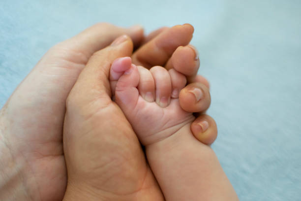 istock Parents hold newborn baby's hand gently 972606464