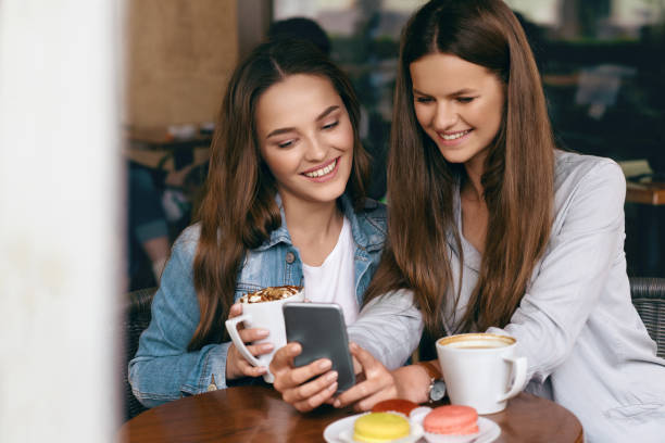 istock Happy Women Using Phone In Cafe. 972643092