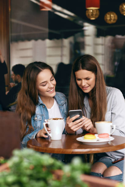 istock Happy Women Using Phone In Cafe. 972647336