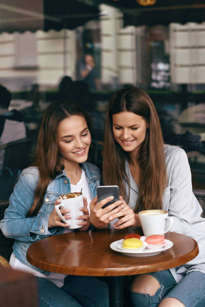 istock Happy Women Using Phone In Cafe. 972647460