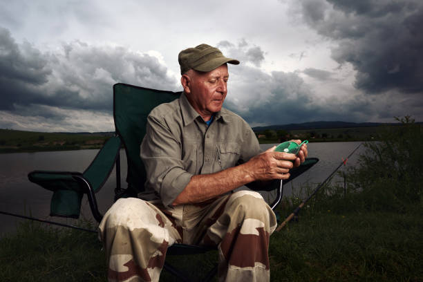 senior man sitting on fishing chair, preparing for capturing some fishes.