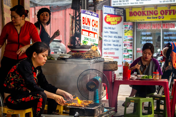 Street barbecue cooking Hanoi Hanoi, Vietnam - March 16, 2018: People working and eating in a street restaurant hot vietnamese women pictures stock pictures, royalty-free photos & images