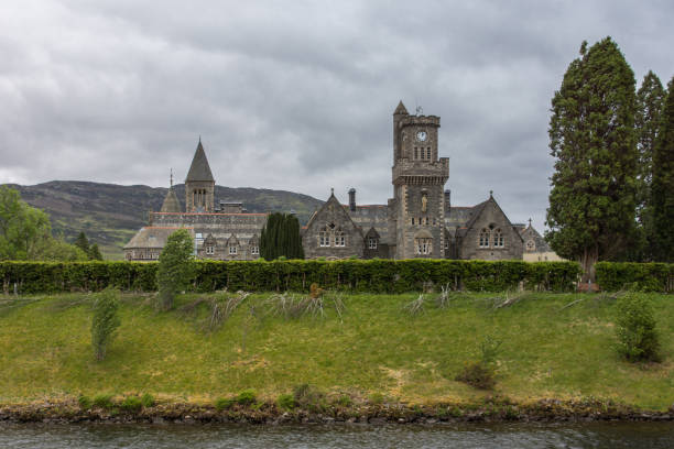 The Abbey Highland Club at Fort Augustus, Scotland. Fort Augustus, Scotland - June 11, 2012: Wide view on the Abbey Highland Club fronted by garden and Oich Canal, under heavy cloudscape. Hills on horizon. fort augustus stock pictures, royalty-free photos & images