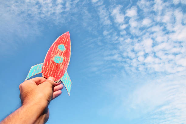 istock image of male hand holding a rocket against the sky. imagination and success concept. 972719404