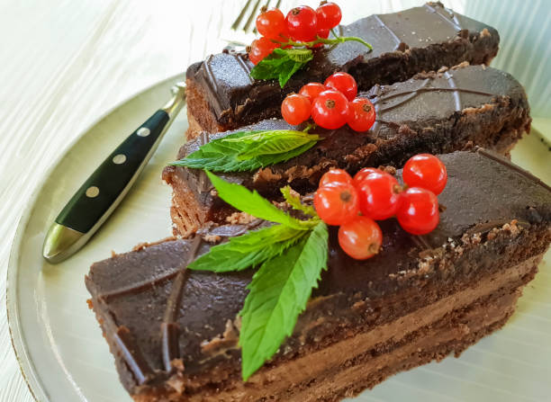 istock chocolate cake, red currant, mint plate on white wooden 972719516