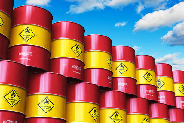 istock Group of red stacked oil drums against blue sky with clouds 972721806