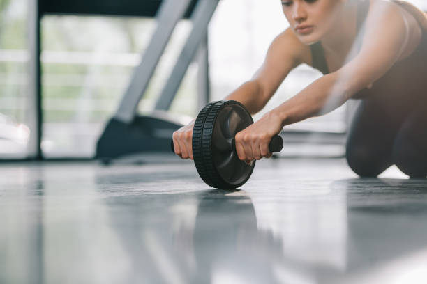 istock cropped image of young sportswoman doing exercise with abs roller at gym 972722006