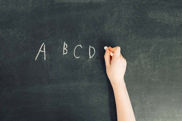 child's hand with chalk write alphabet on black chalkboard child's hand with chalk write letters a, b, c, d on black chalkboard, stock photo image b c stock pictures, royalty-free photos & images