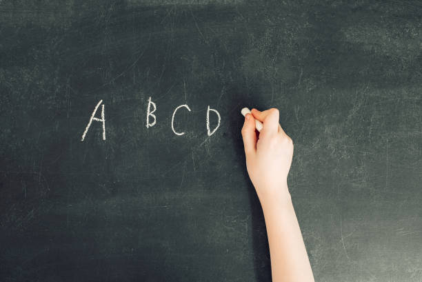 child's hand with chalk write alphabet on black chalkboard - blackboard teaching preschool alphabet imagens e fotografias de stock