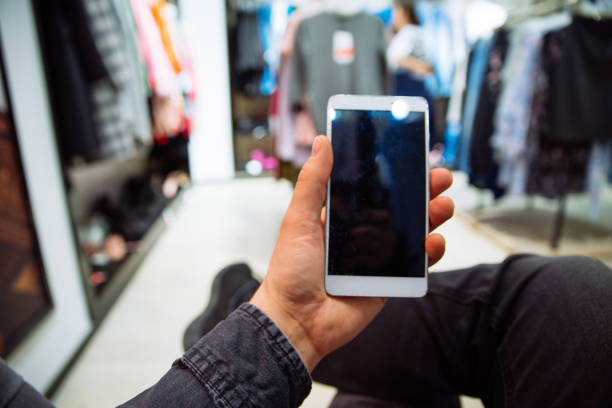 istock man looking into phone while his girlfriend do shopping in boutique 972739862