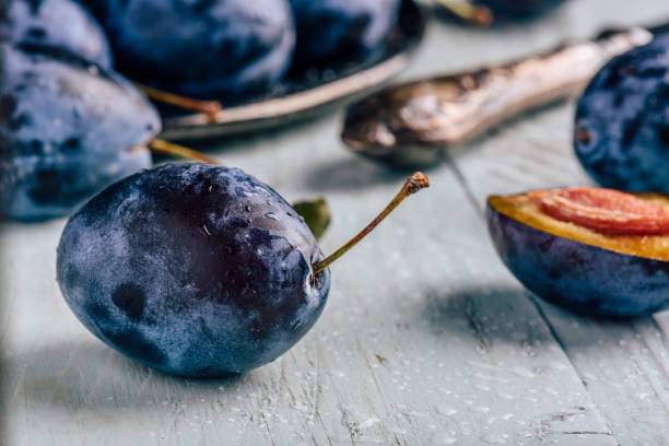 istock Plums with leaves and knife over wooden surface 972746842