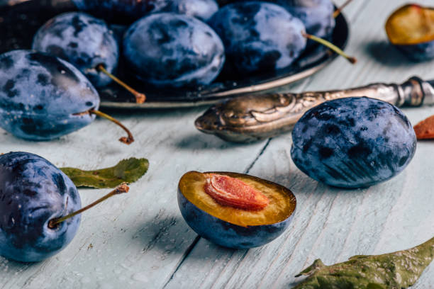 istock Plums with leaves and knife over wooden surface 972746852