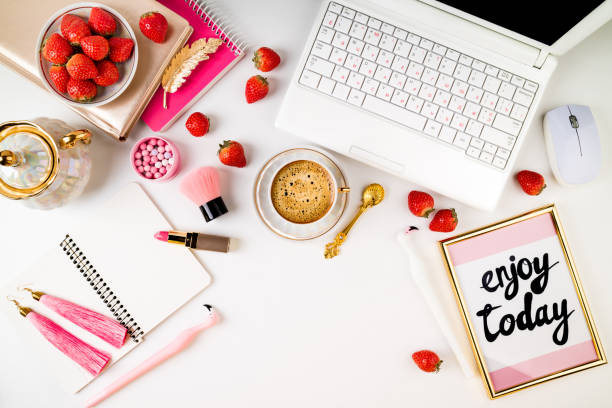 istock Trendy feminine home workplace. Home office desk with laptop, notebook, fresh strawberries, cosmetics, accessories and coffee cup on white background. Flat lay 972764010