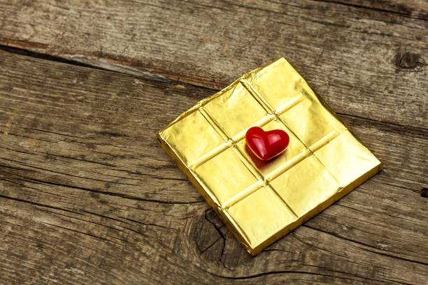 istock Bitter chocolate in a gold foil on a wooden board. Chocolate delicacy. 972767016