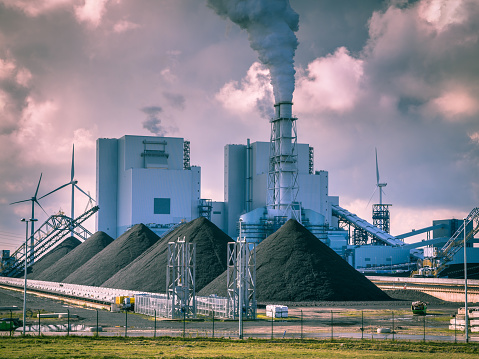 Old fashioned industrial coal powered electricity plant with pipes and smoke in black and white