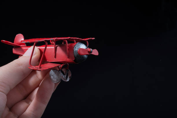 istock Hand holding a toy plane on black background 972781954