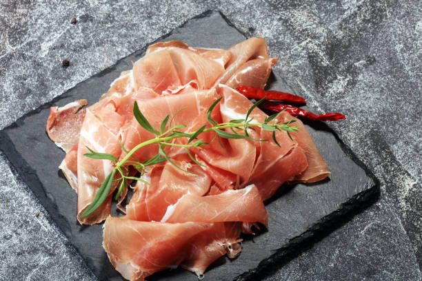 istock Italian prosciutto crudo or jamon with parsley. Raw ham 972785206