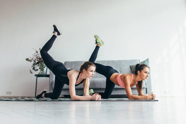 istock Two fit women doing bent knee donkey kick exercise in all fours position working out their buttocks at home 972788204