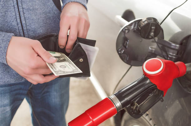 Expensive fuel. Lack of money for gasoline and fuel. Expensive gasoline. Driver man holds one dollar end empty wallet against the background of a fuel nozzle in the gas tank. increase in gasoline prices concept. wallet gun stock pictures, royalty-free photos & images