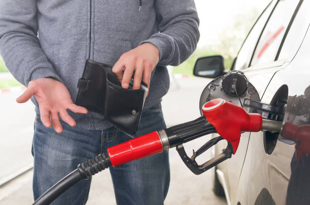 Expensive fuel. Lack of money for gasoline and fuel. Expensive gasoline. Driver man holds one dollar end empty wallet against the background of a fuel nozzle in the gas tank. increase in gasoline prices concept. fuel prices photos stock pictures, royalty-free photos & images