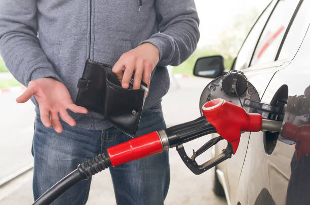 Expensive fuel. Lack of money for gasoline and fuel. Expensive gasoline. Driver man holds one dollar end empty wallet against the background of a fuel nozzle in the gas tank. increase in gasoline prices concept. wallet gun stock pictures, royalty-free photos & images