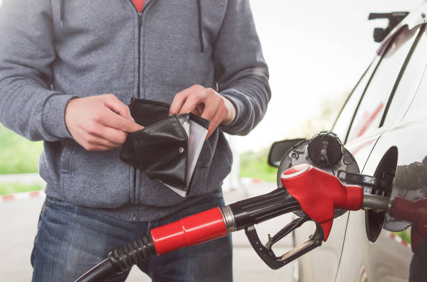 Expensive fuel. Lack of money for gasoline and fuel. Expensive gasoline. Driver man holds one dollar end empty wallet against the background of a fuel nozzle in the gas tank. increase in gasoline prices concept. wallet gun stock pictures, royalty-free photos & images